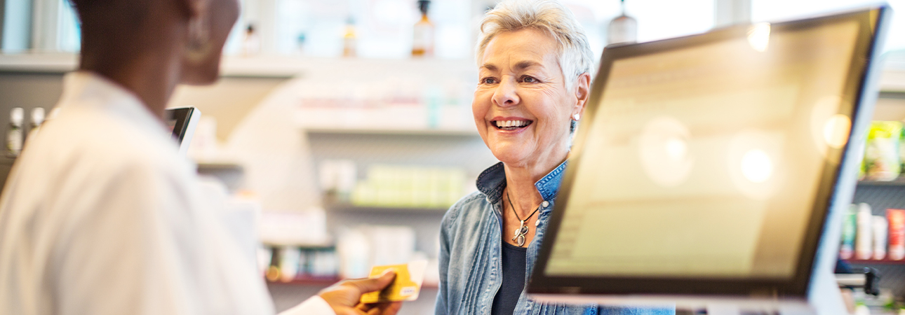 An older woman smiling as she talks to pharmacist.