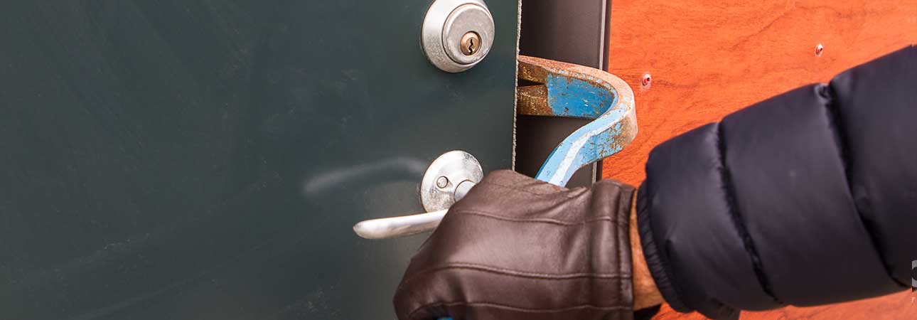 Image of a hand using a crow bar to open a building door