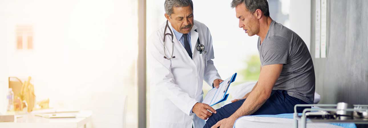 Medical doctor examining a man's knee at a doctor's office