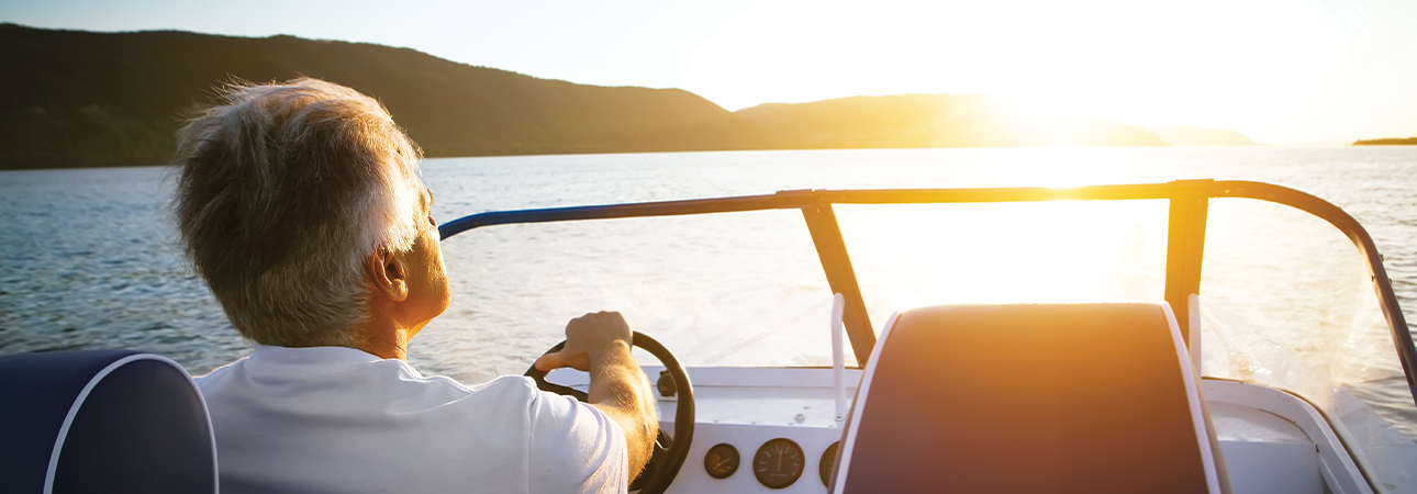 Man steering power boat through lake water